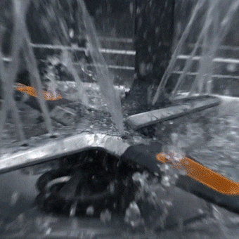 Bras d'aspersion en croix d'un lave-vaisselle projetant des jets d'eau sur une cuve en acier inoxydable.